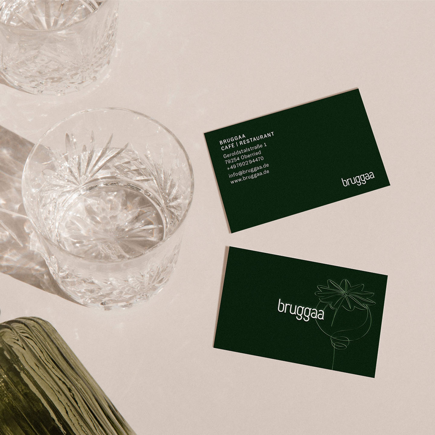 bright photography of various glasses and two business cards with a continuous line illustration of poppy