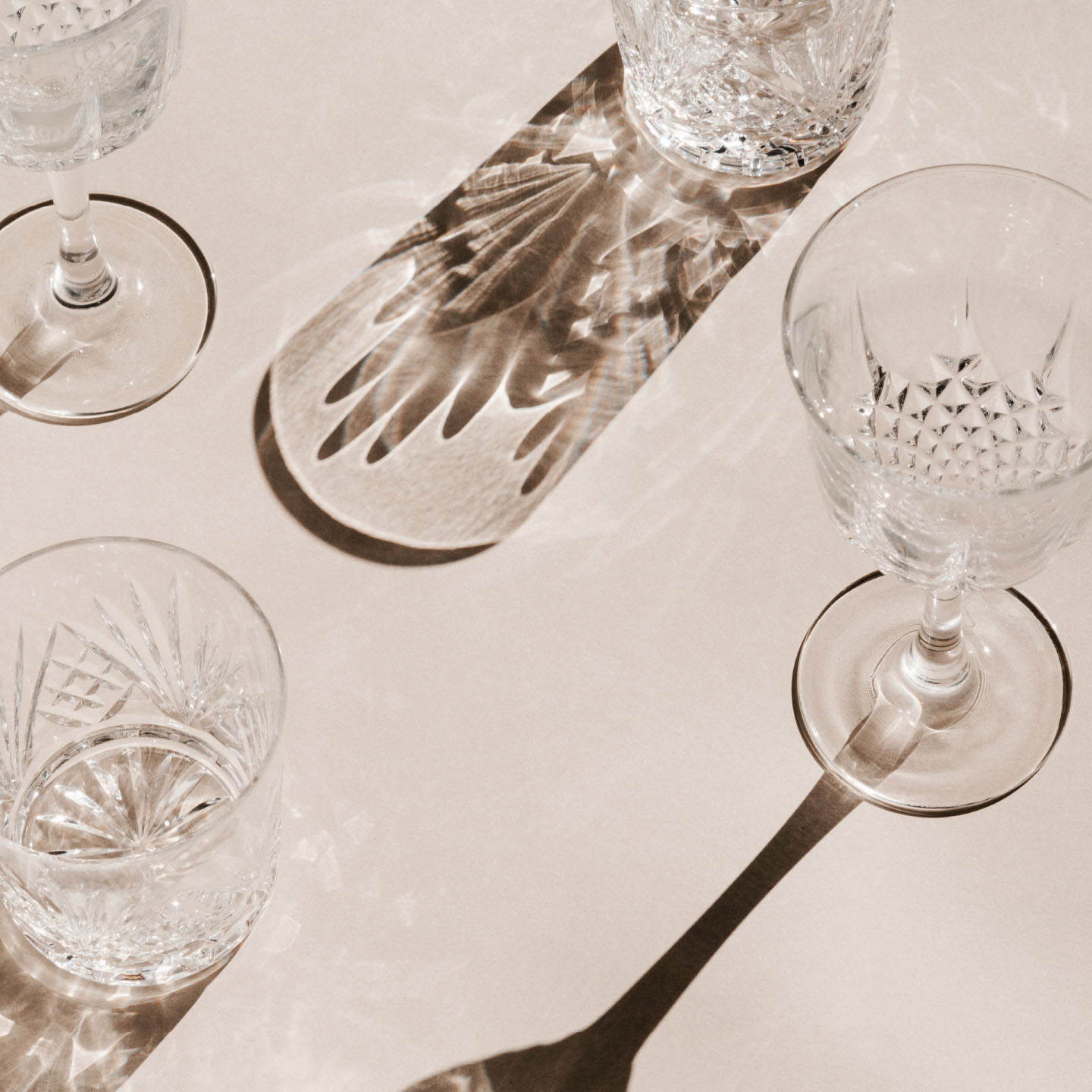 high contrast photography of various wine and cocktail glasses with long shadows