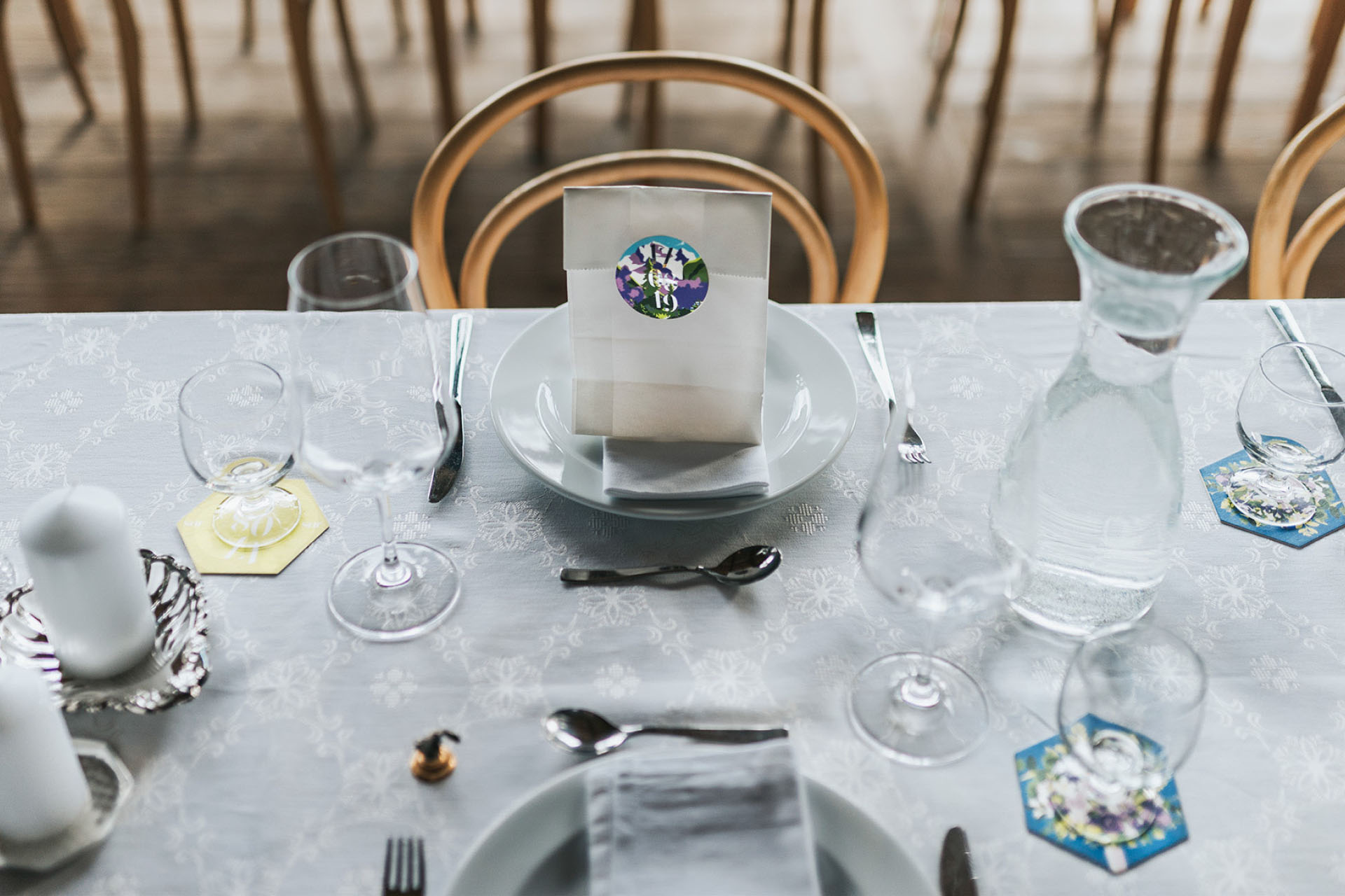 set table at a wedding with coasters and giveaways, closed with a sticker with an illustration and silver foil lettering